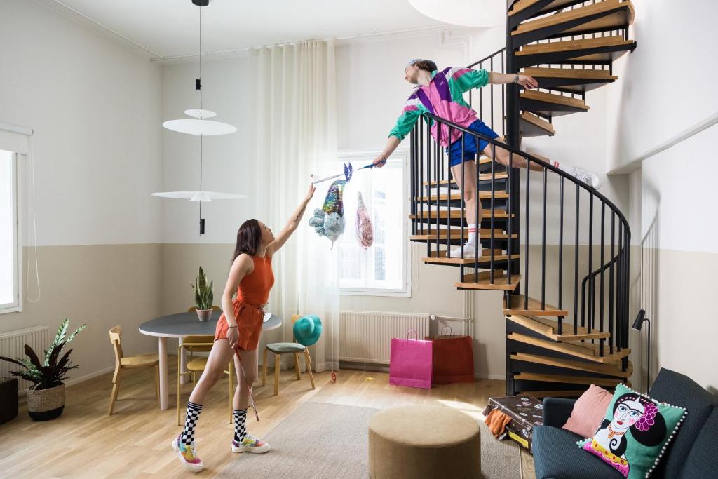 two people are hanging clothes on a spiral staircase in a living room at Bob W Helsinki City Centre in Helsinki