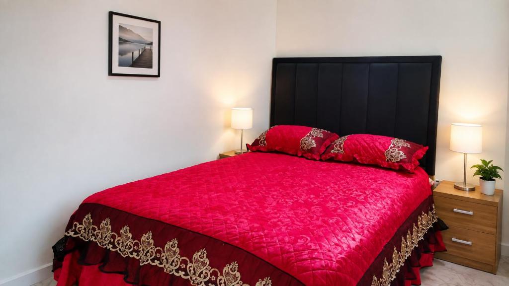 a bedroom with a large red bed with two lamps at Optizee Hotel and Suites in Agege