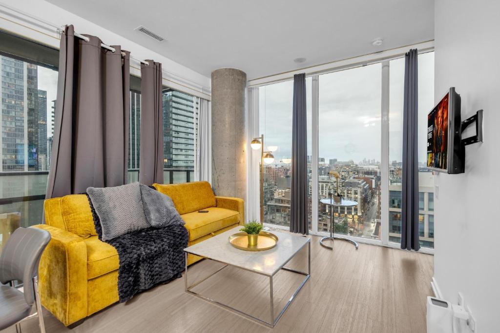 a living room with a yellow couch and large windows at Toronto Skyline Center Hotel in Toronto