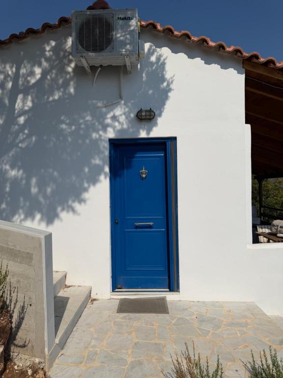 a blue door on the side of a white house at Calmora by the Sea in Ancient Epidauros