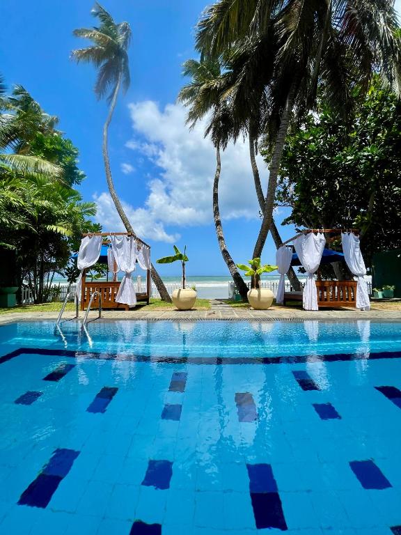 a pool at a resort with palm trees at Baia Dikwella in Batigama