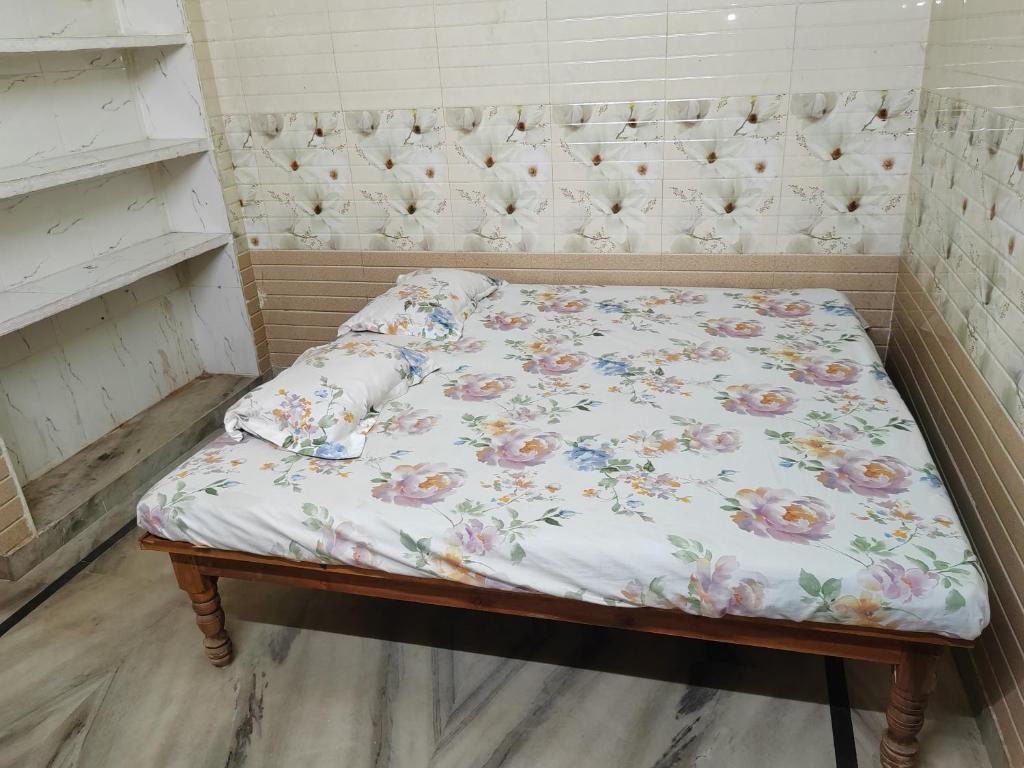 a small bed with a floral sheet on it at Harekrishna Nilayam in Vemalwāda