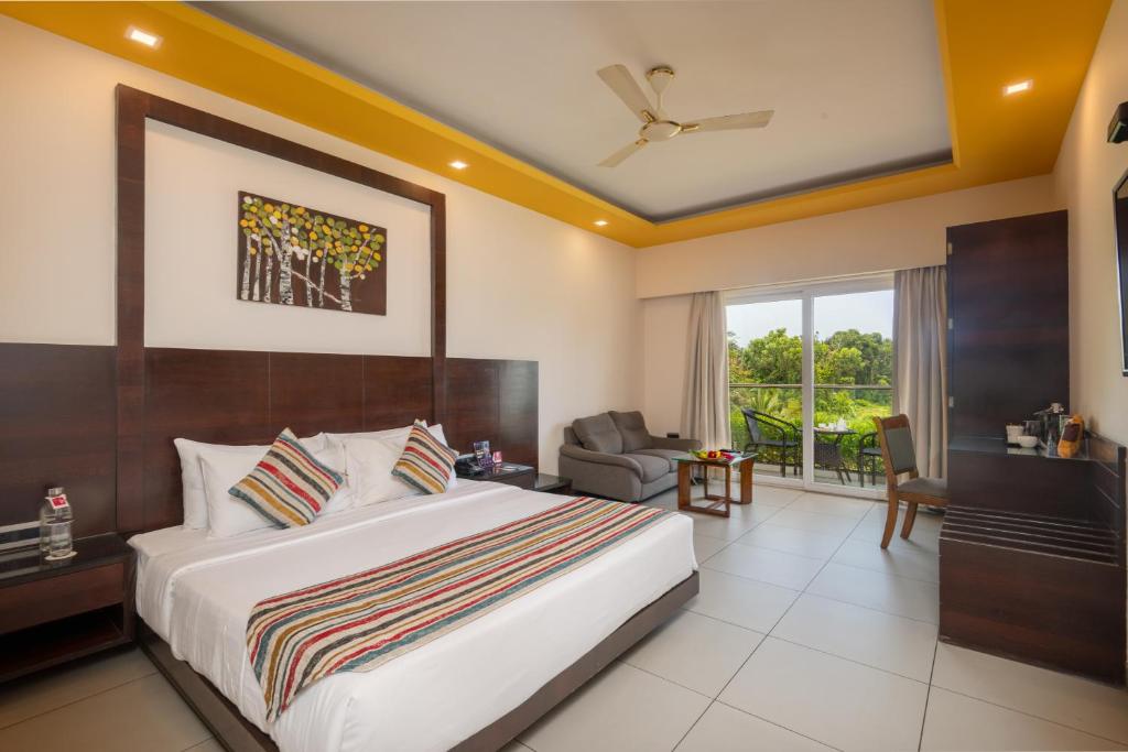 a hotel room with a large bed and a chair at Regenta Central North Goa, Arpora in Arpora