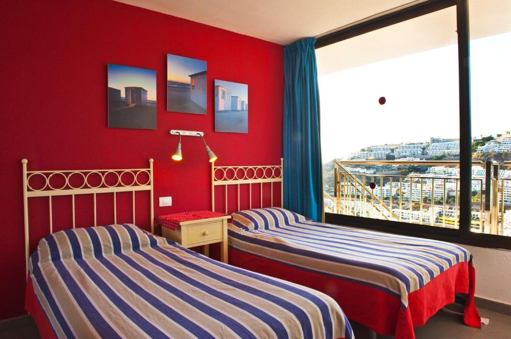 2 Betten in einem Zimmer mit roten Wänden in der Unterkunft Apartamentos Miriam in Puerto Rico de Gran Canaria