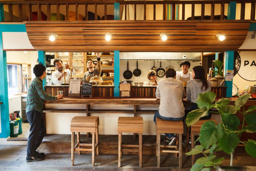 un grupo de personas sentadas en un bar en un restaurante en The Pax Hostel, en Osaka
