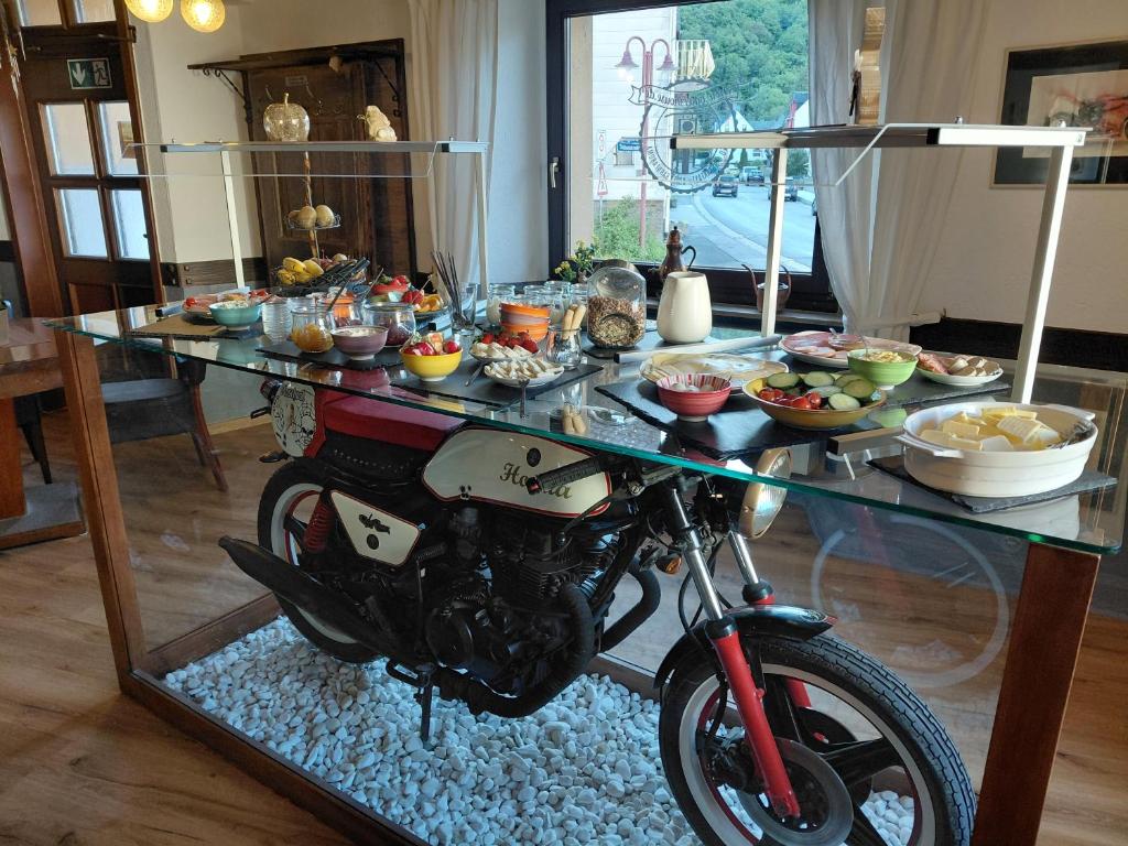 a motorcycle parked in front of a table of food at Moselblick Hotel Aroma Bikershouse in Burgen