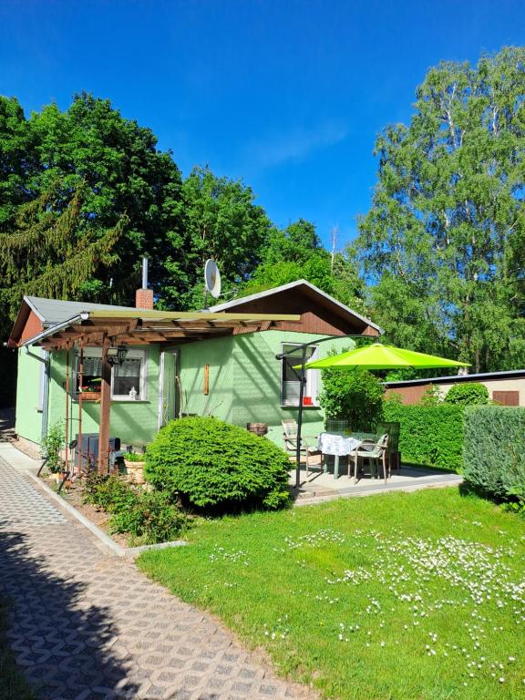 a green house with a table and a patio at Ferienhaus Hilde in Sangerhausen