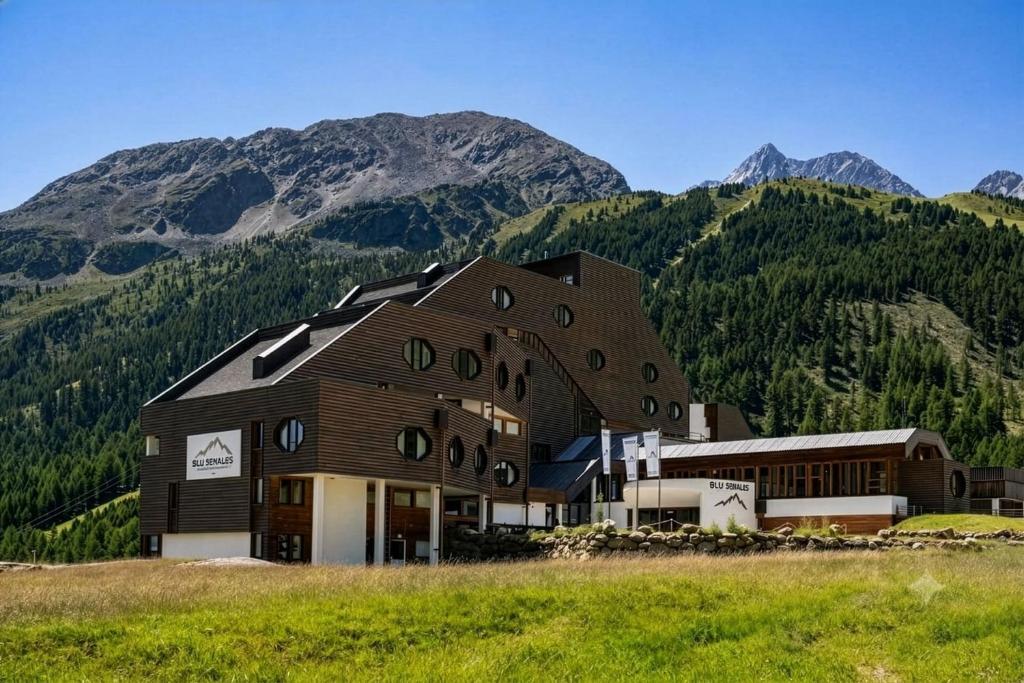 a large building with mountains in the background at Blu Senales Active & Family Resort in Maso Corto