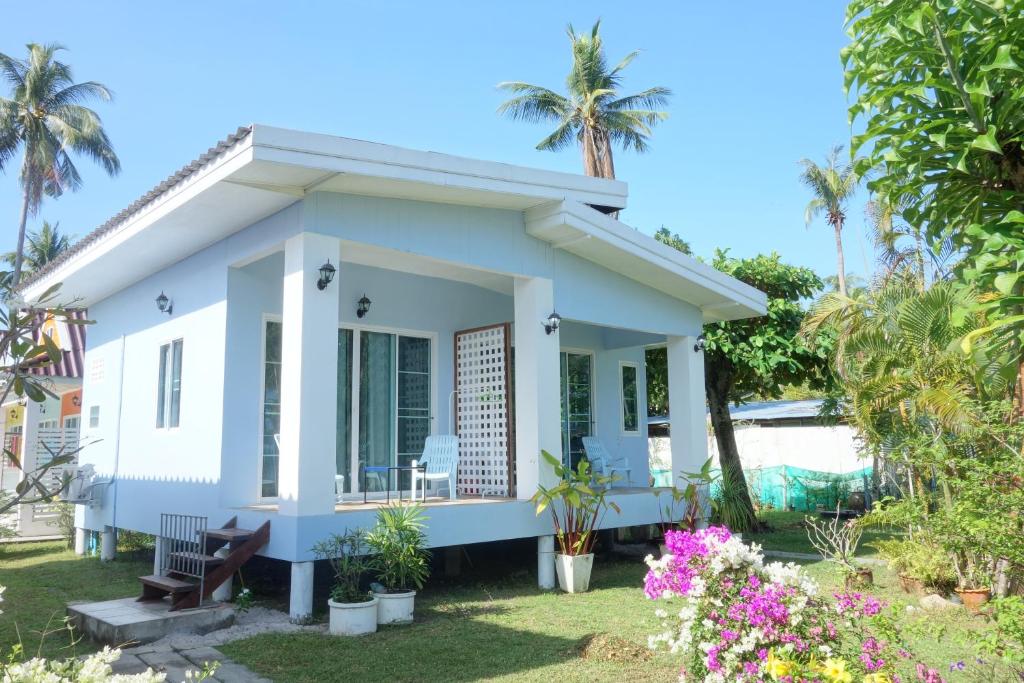 a small white house with palm trees and flowers at Mook Ing Lay in Ko Mook