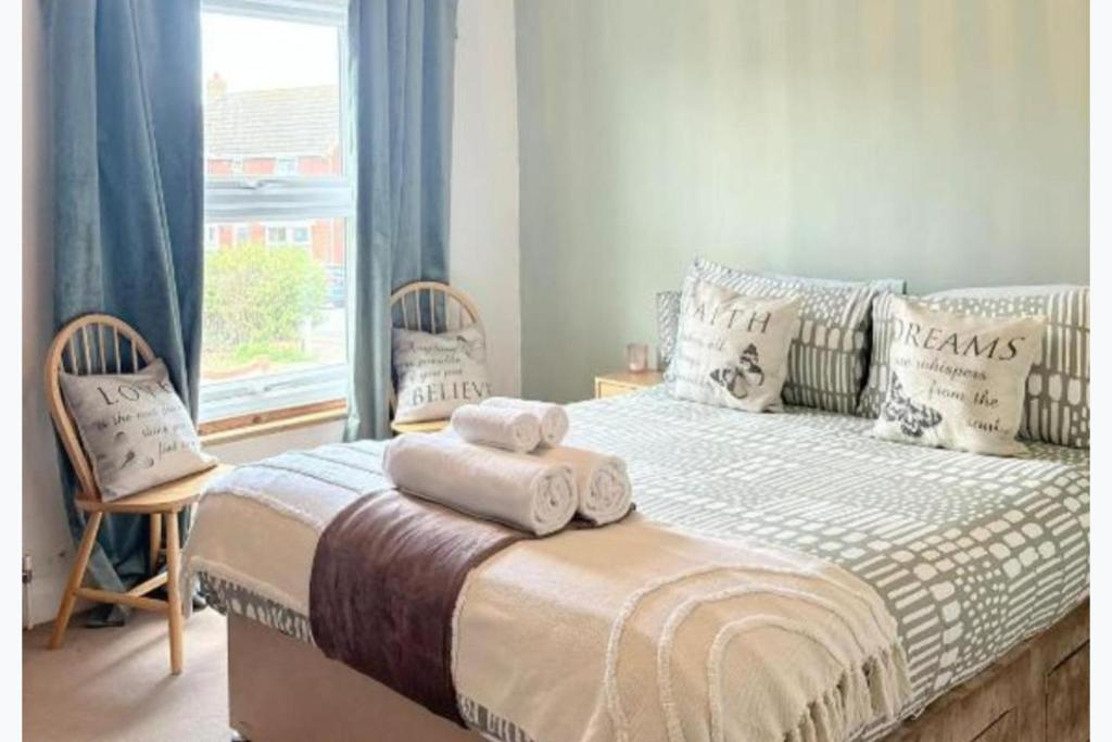 a bedroom with a bed with two chairs and a window at Walton Beach 1-Bed Cottage Sleeps 2 with Parking in Walton-on-the-Naze