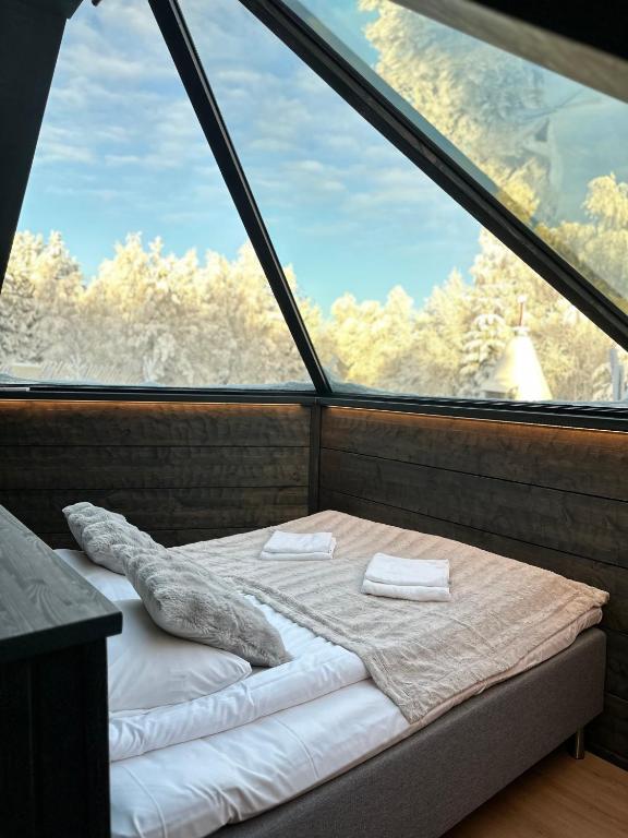 a bed in a room with a large window at Shaman Village - Resort & Glass Igloos in Rovaniemi
