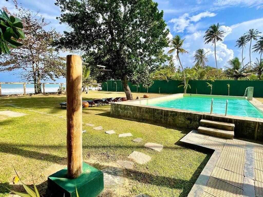 a swimming pool with a wooden pole in the grass at Lido Dikwella in Dickwella