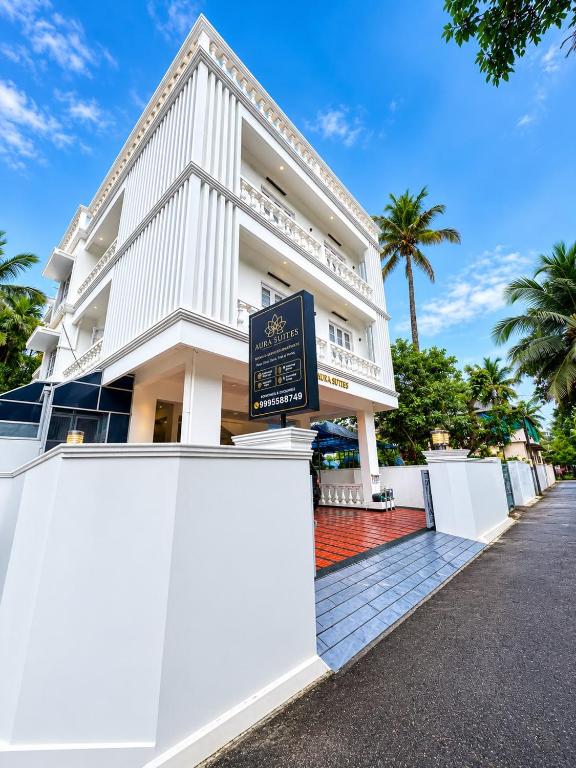 a white building with a sign in front of it at Aura Suites Chernallur in Ernakulam