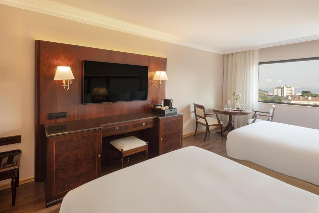 A bedroom seating area faces a wall-mounted television and built-in wood storage beside the bed.