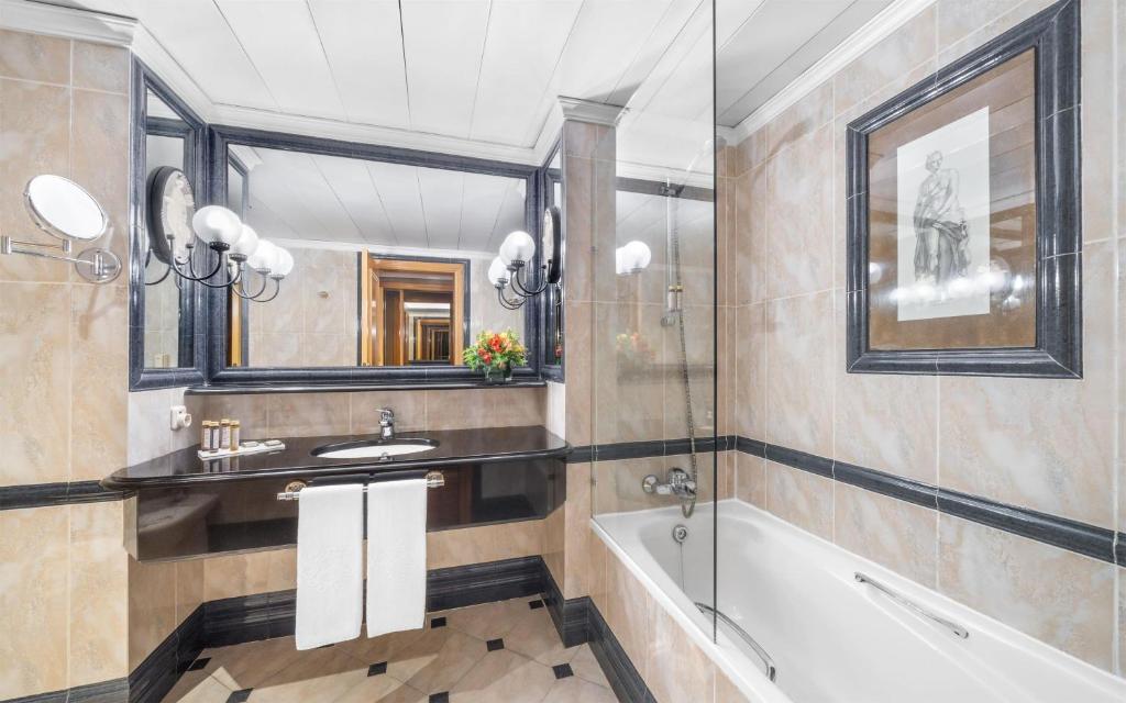 A marble bathroom with a bathtub, vanity and large mirror.