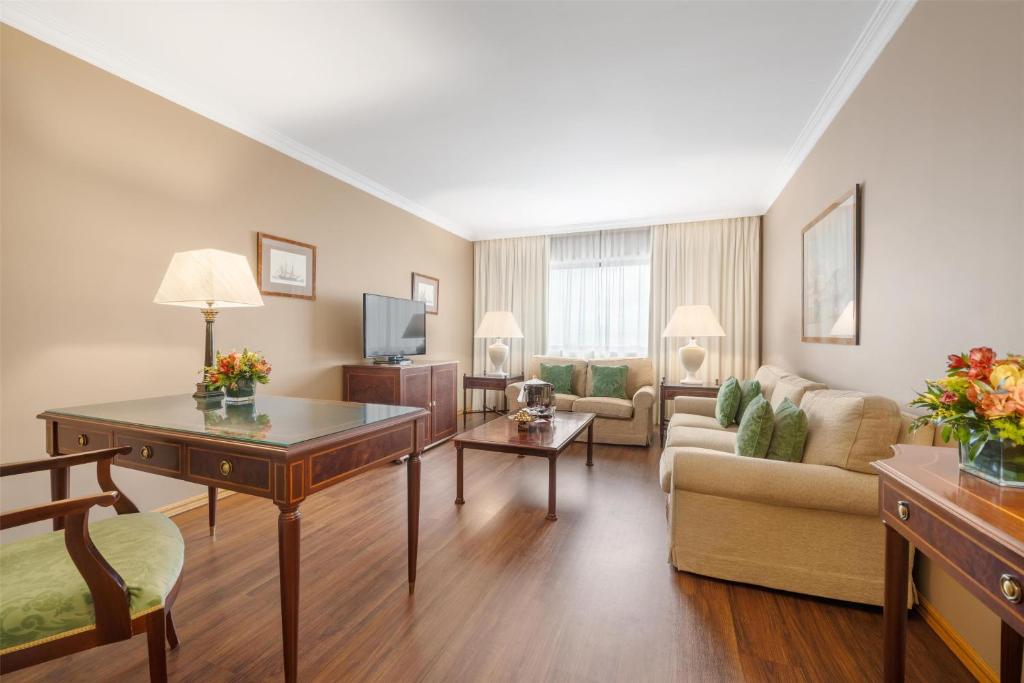 A spacious traditional sitting room with sofas, desk and television.