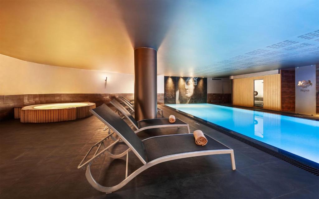 An indoor pool and whirlpool with loungers in a dark spa setting.