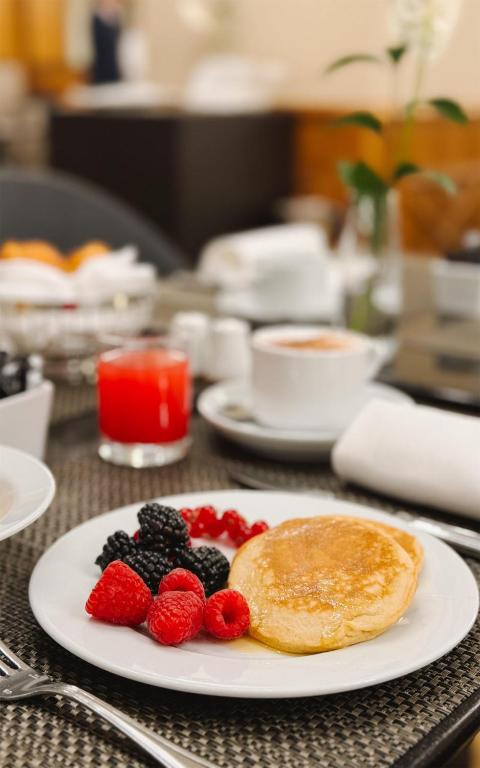 Pancakes with berries are served beside coffee and a red drink.