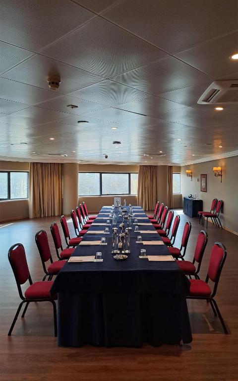 A formal conference room with a long fully set table beside large windows.