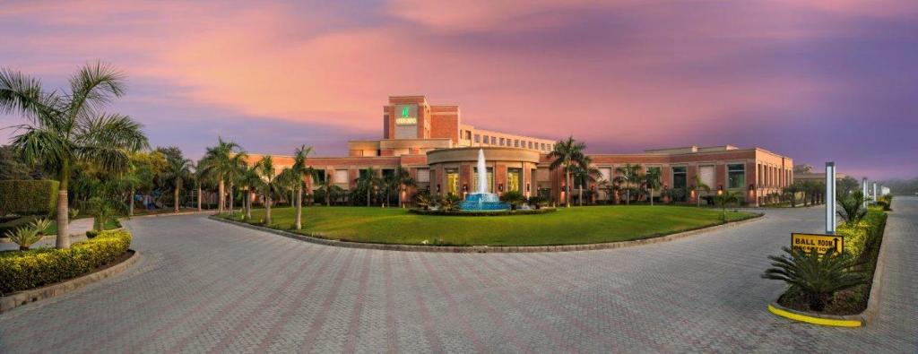 a large building with palm trees in front of it at NIRVANA Luxury Hotel l Ludhiana in Ludhiana