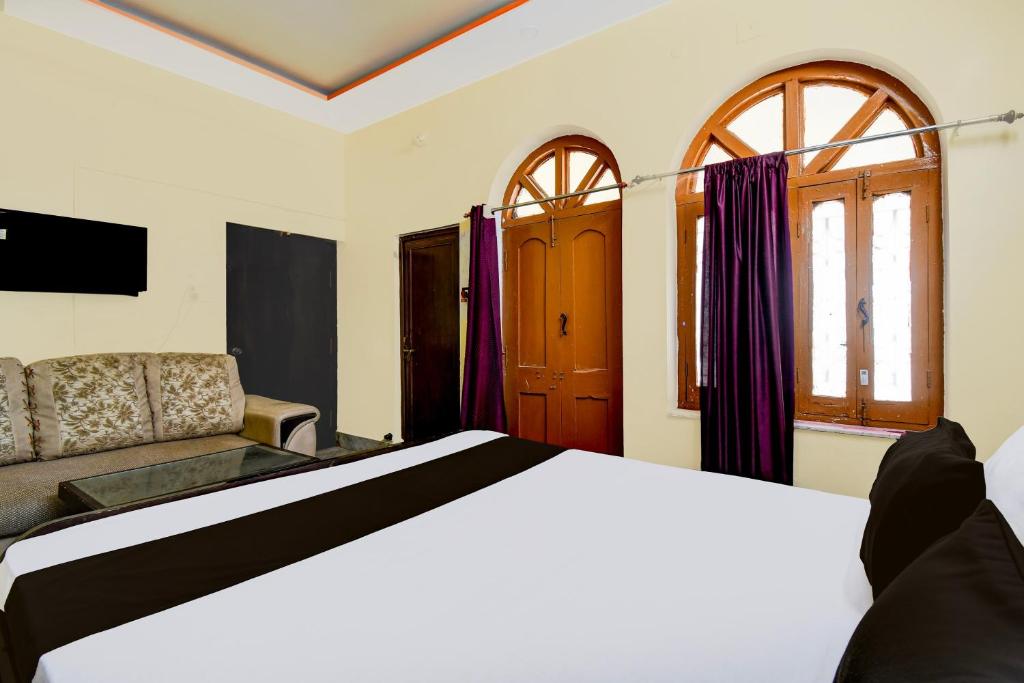 a bedroom with a bed and a couch and windows at Hotel O Magadh Guest House in Gaya