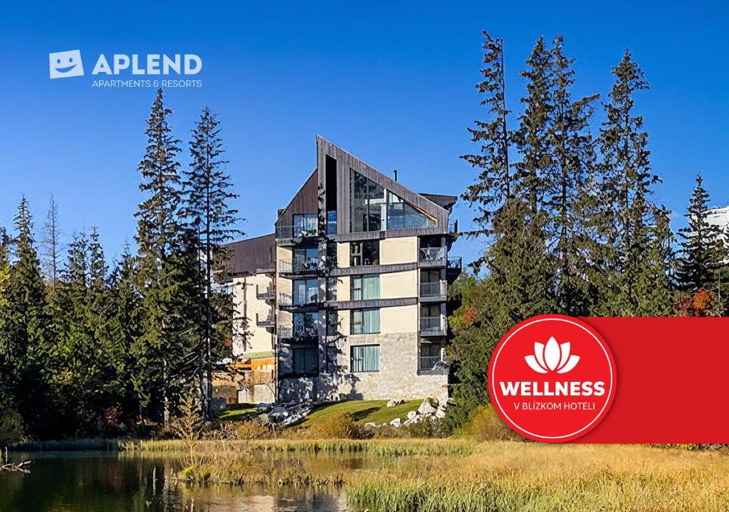 a building with a sign in front of a lake at APLEND Lake Resort in Štrbské Pleso