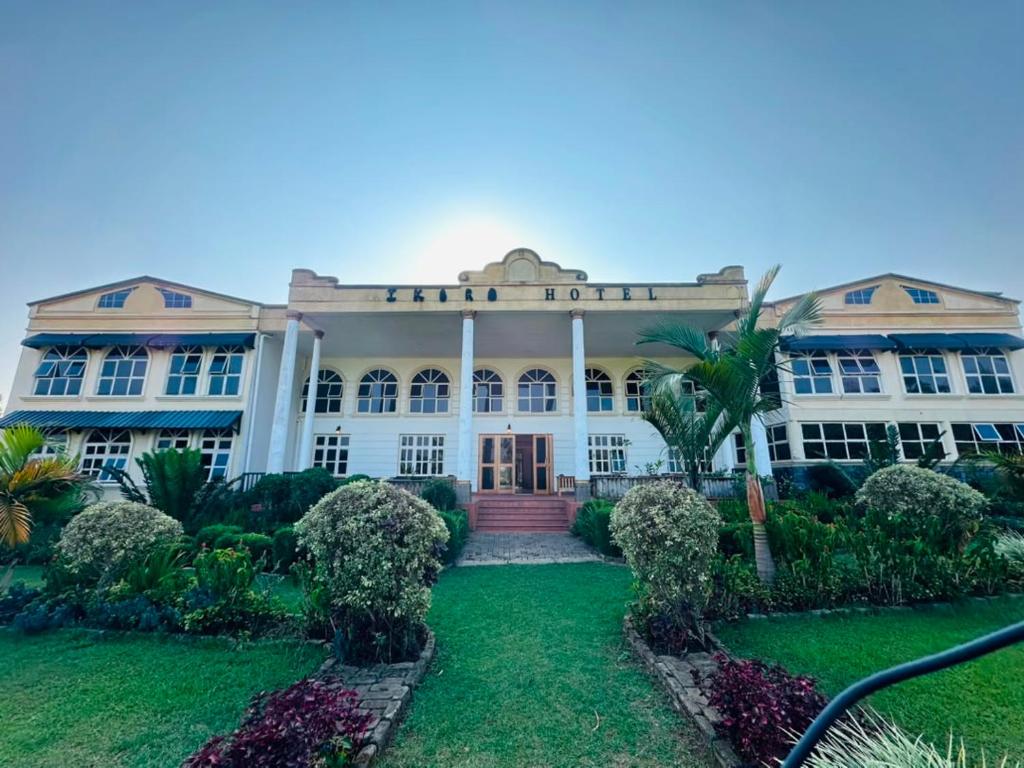a large white building with a garden in front of it at Ikoro Hotel in Kisoro