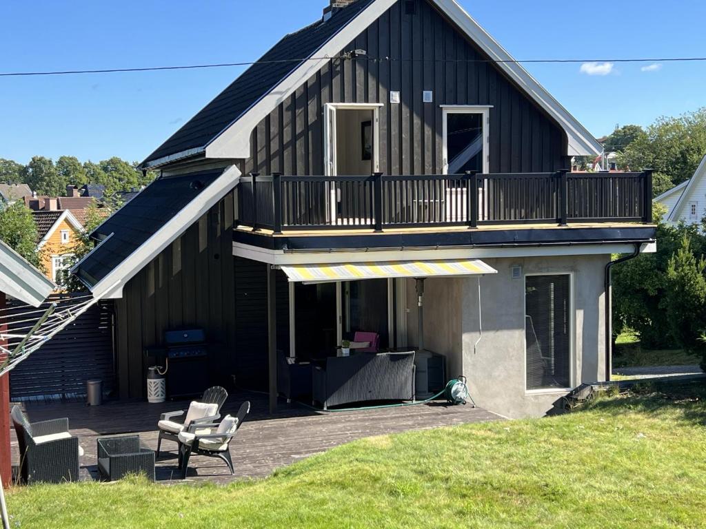 a black house with a deck and a balcony at Charming Villa Central Moss in Moss