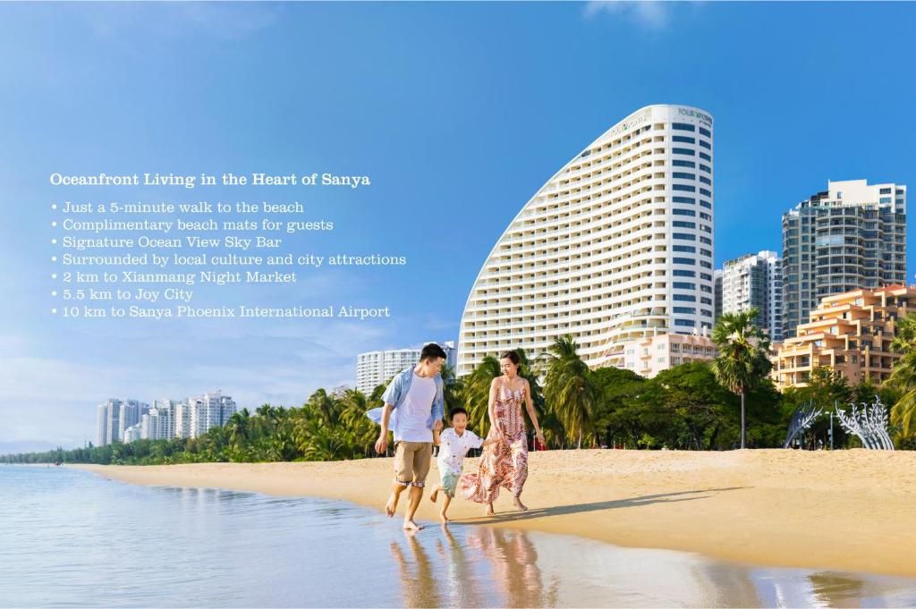 a family walking on the beach with buildings in the background at Four Points by Sheraton Hainan, Sanya in Sanya
