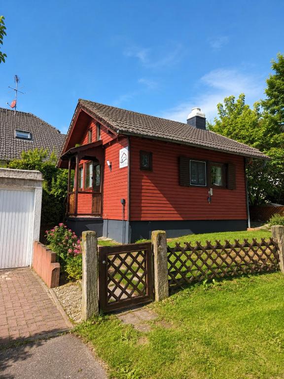 a red house with a fence in front of it at Ferienhaus Tinyhouse21 Wasserkuppe in Gersfeld