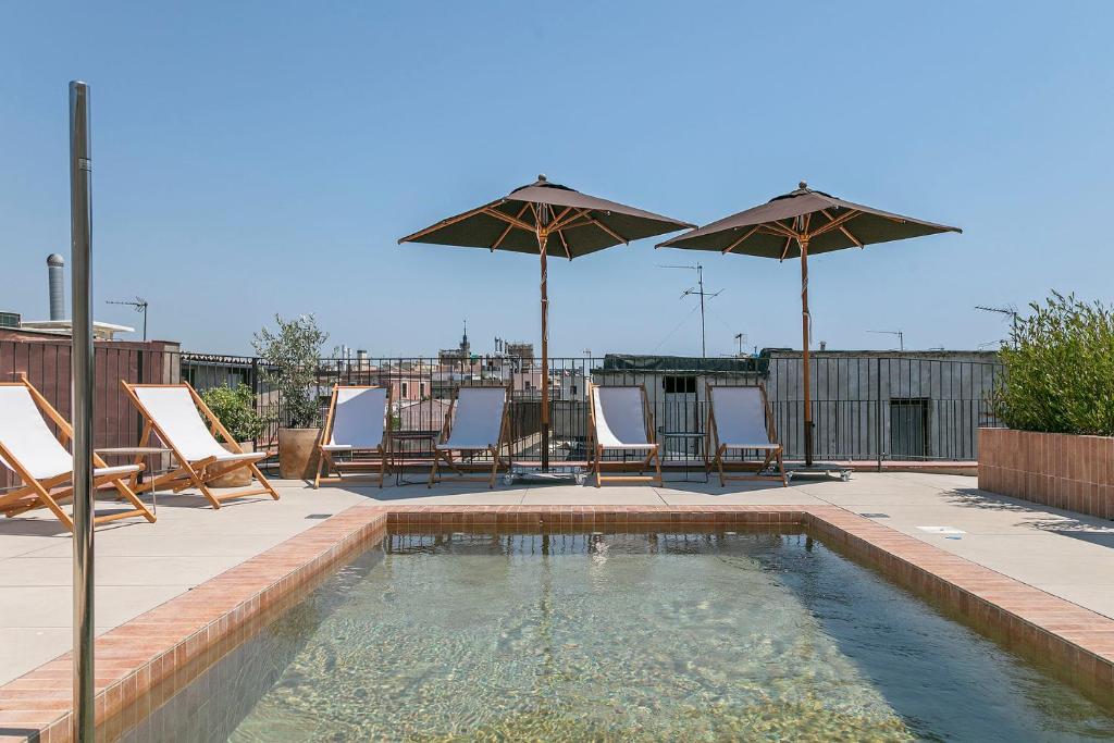 a pool with chairs and umbrellas on a patio at Andante Princesa in Barcelona