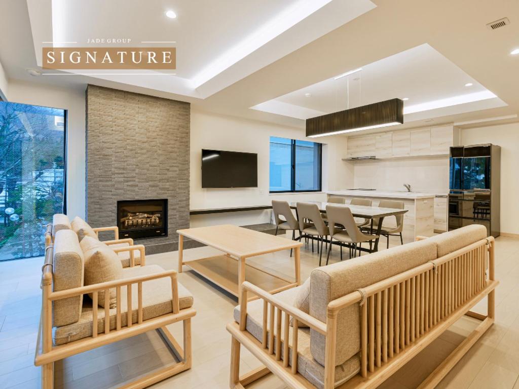a living room with tables and chairs and a fireplace at Grand Phenix Hakuba by Jade Villa in Hakuba
