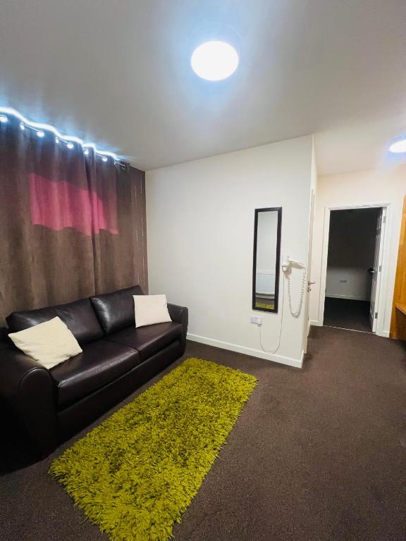 a living room with a black couch and a yellow rug at Central Hotel Gloucester in Gloucester