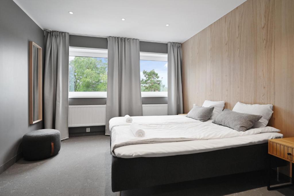 a bedroom with a large bed and two windows at Måby Park Hotel Arlanda in Arlanda