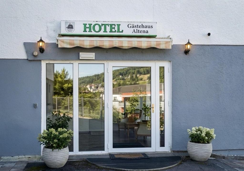 a hotel with two potted plants in front of a building at Hotel Gästehaus Altena in Altena