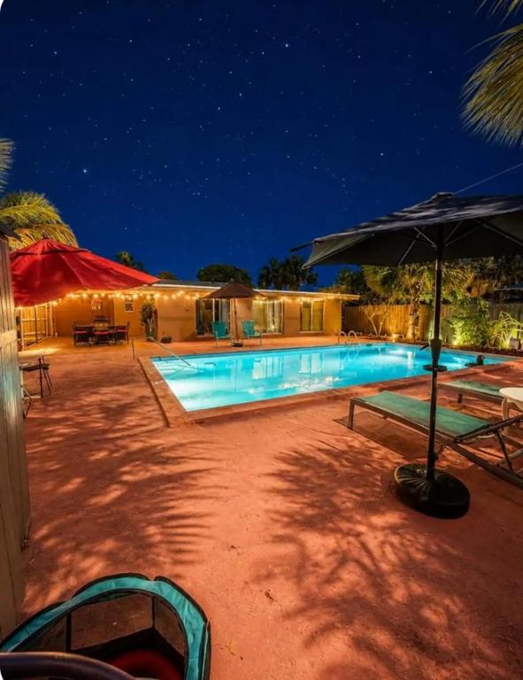 a swimming pool with an umbrella at night at Perfect Family Group Getaway in West Palm Beach