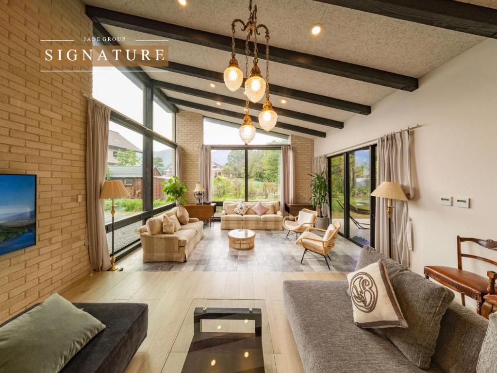 a living room with couches and chairs and windows at Hakuba Jolie Maison by Jade Villa in Hakuba