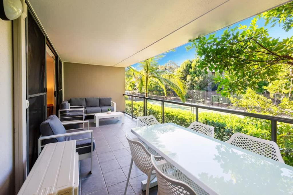 a balcony with tables and chairs and a large window at Azure Beach Retreat 2 in Rainbow Beach