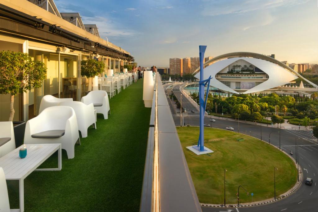 a balcony of a building with white chairs and a highway at Barceló Valencia in Valencia