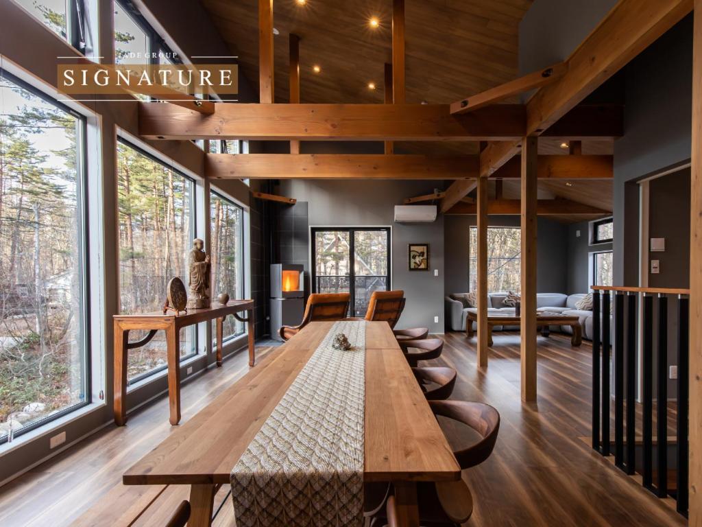 a large wooden table in a room with windows at Oradoro Chalet Hakuba by Jade Villa in Hakuba