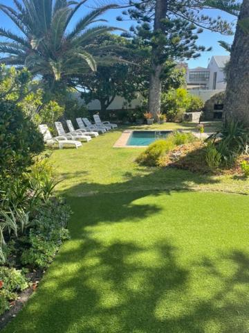a yard with white chairs and a swimming pool at House on Westcliff in Hermanus