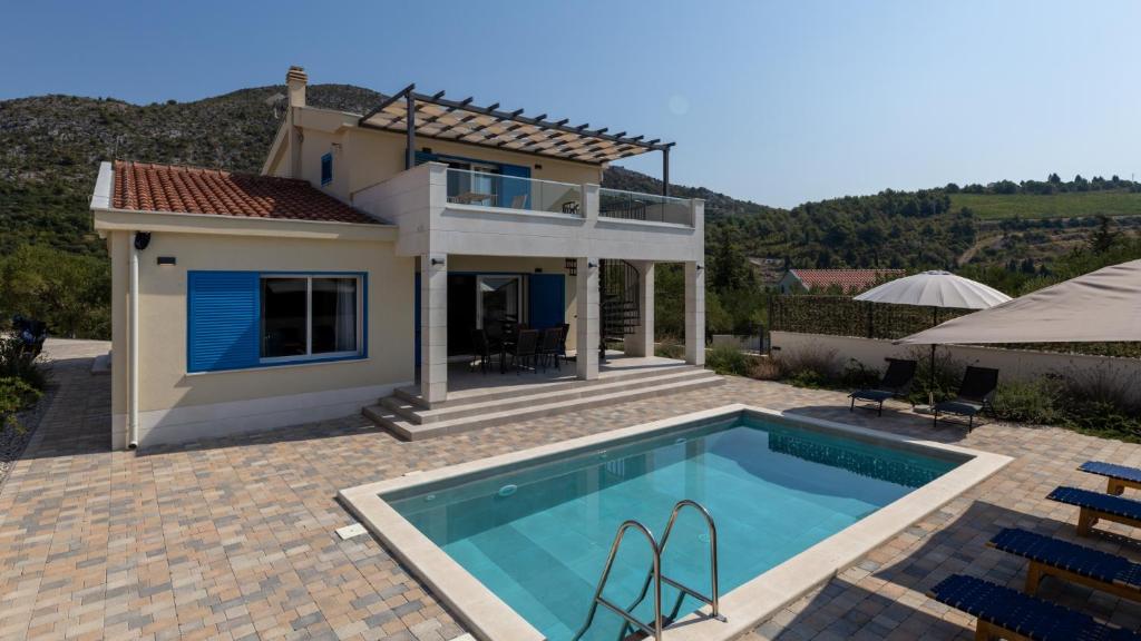 a villa with a swimming pool in front of a house at Villa Olea by Villas Guide in Blace