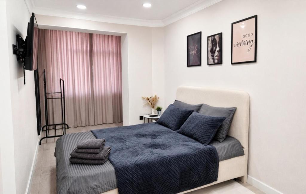 a bedroom with a bed with a blue comforter at Sunset Apartment Aktau Квартира в центре у моря in Aktau