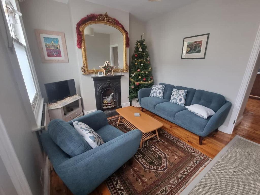 a living room with two blue couches and a christmas tree at Central Cambridge -comfortable Victorian Terrace in Cambridge