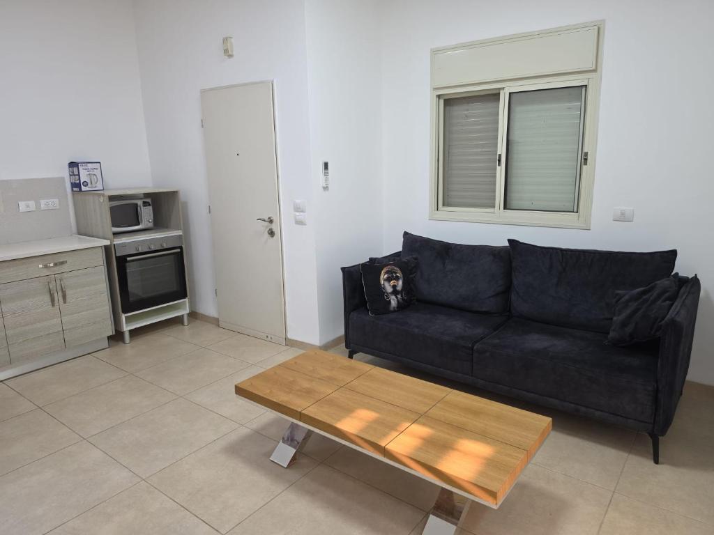 a living room with a black couch and a coffee table at פנינת הצפון in Qiryat Shemona