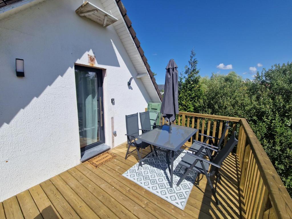 a wooden deck with a table and an umbrella at La maison des Hirondelles 2 in Fort-Mahon-Plage
