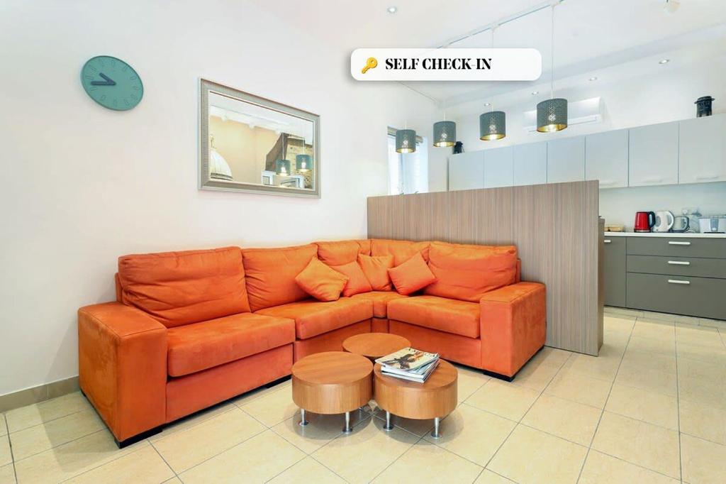 a living room with an orange couch and a table at Ta Gianni Guest House Sliema in Sliema