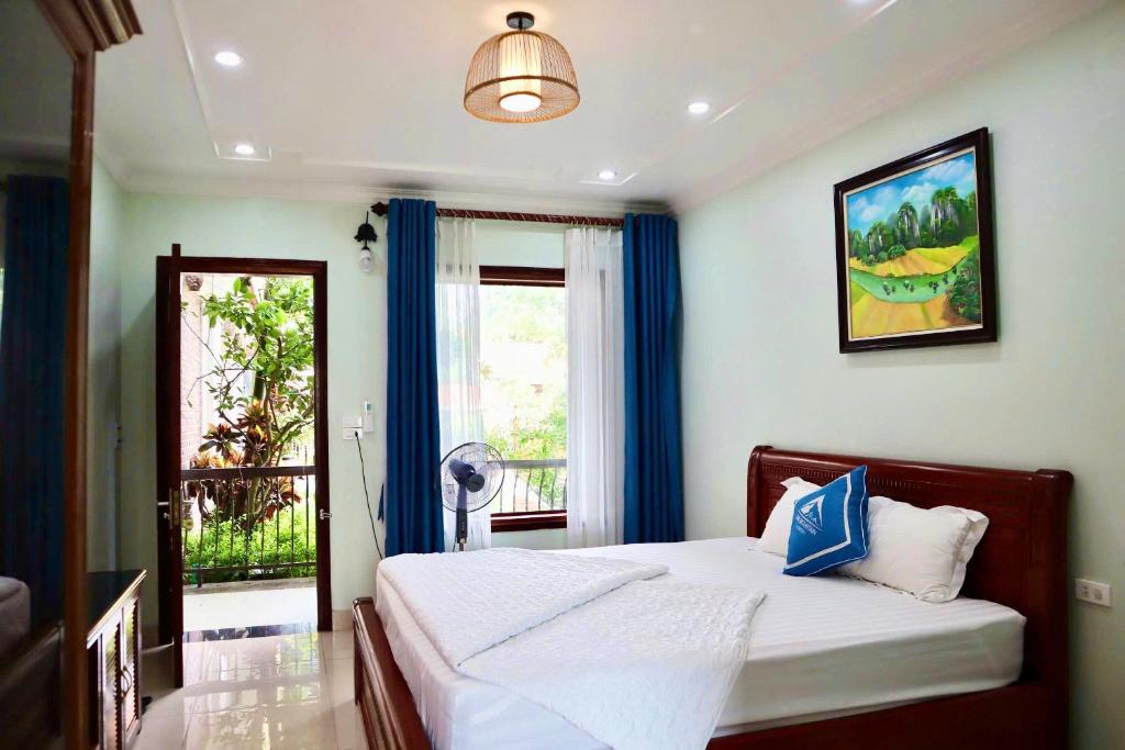 a bedroom with a bed with blue curtains and a window at Mai Mountain Homestay in Ninh Binh