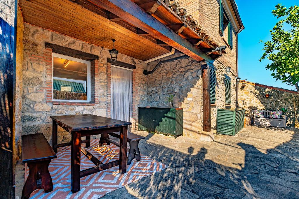 a wooden table on a patio with a stone wall at El Regreso in Jarilla