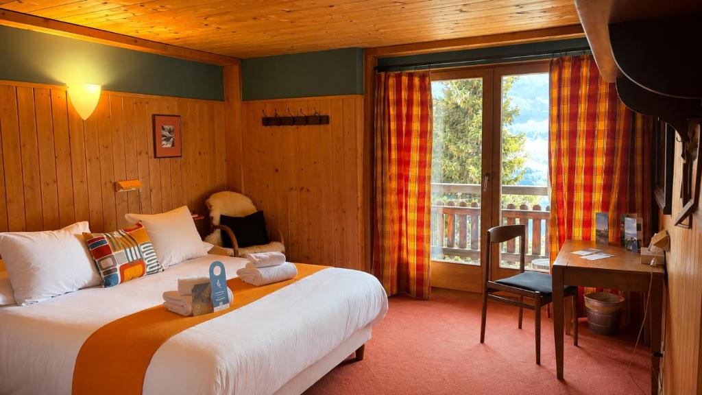 a bedroom with a bed and a desk and a window at Plein Ciel - Hôtel d'altitude à 1800m in Champéry